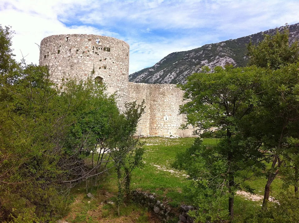 Stone tower and green hillside at Drivenik Castle
